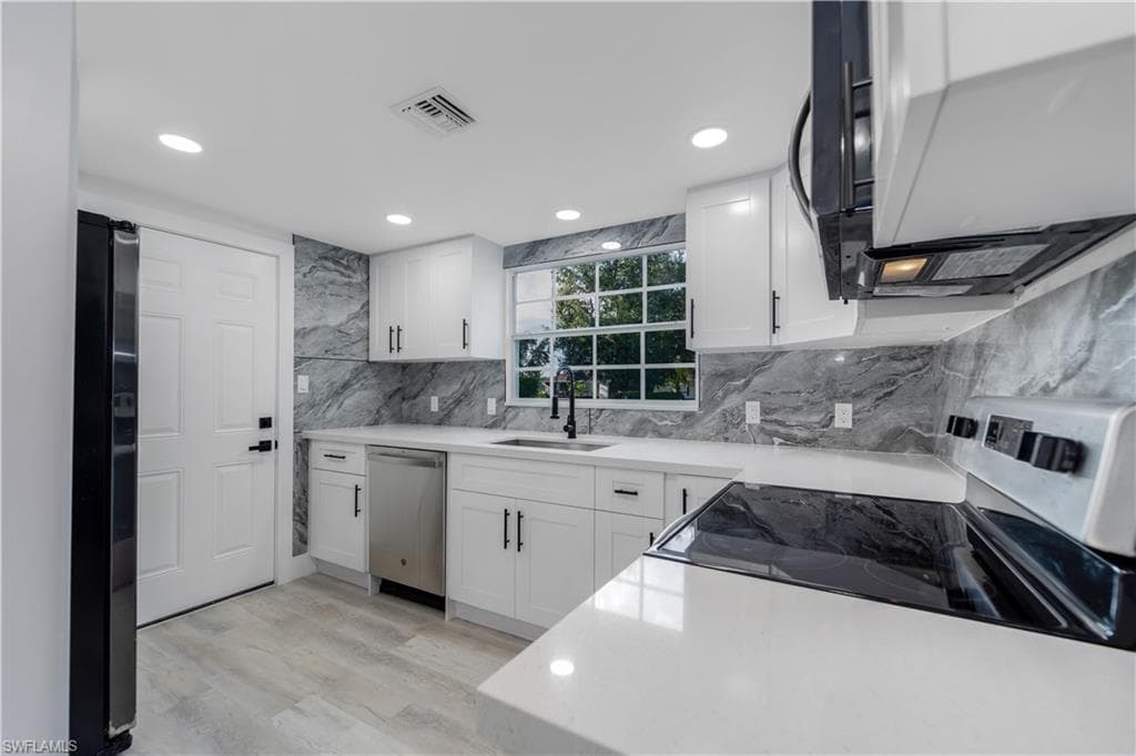 Kitchen with fridge with ice dispenser, white cabinetry, light stone countertops, light wood-style flooring, and recessed lighting