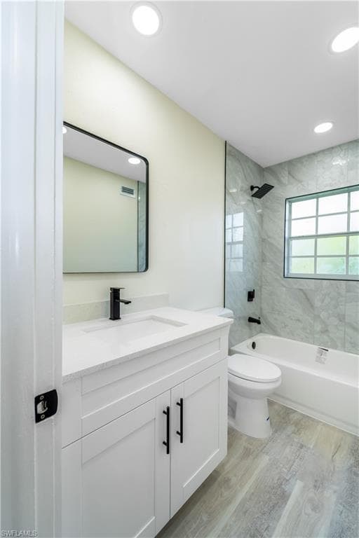 Bathroom featuring shower / tub combination, vanity, light wood-type flooring, and recessed lighting