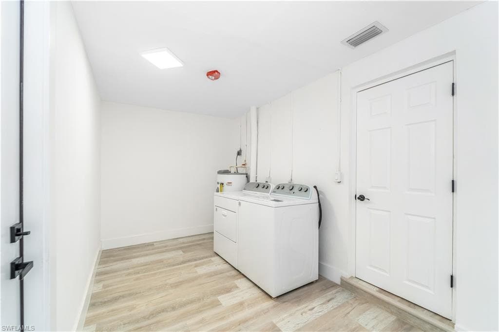 Full bathroom featuring two vanities, light wood-style floors, and a marble finish shower