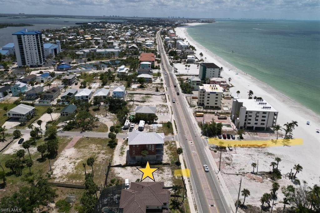 Aerial view of property and surrounding area featuring extended coastline and nearby urban area