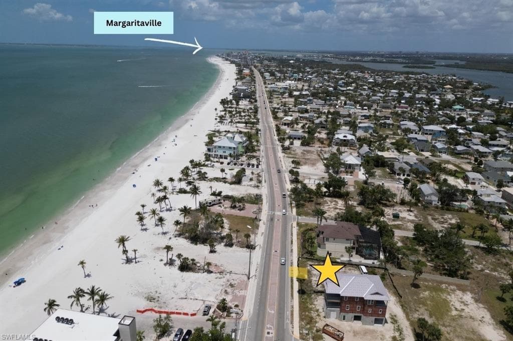 Aerial view of property and surrounding area with waterfront with a beach and nearby suburban area