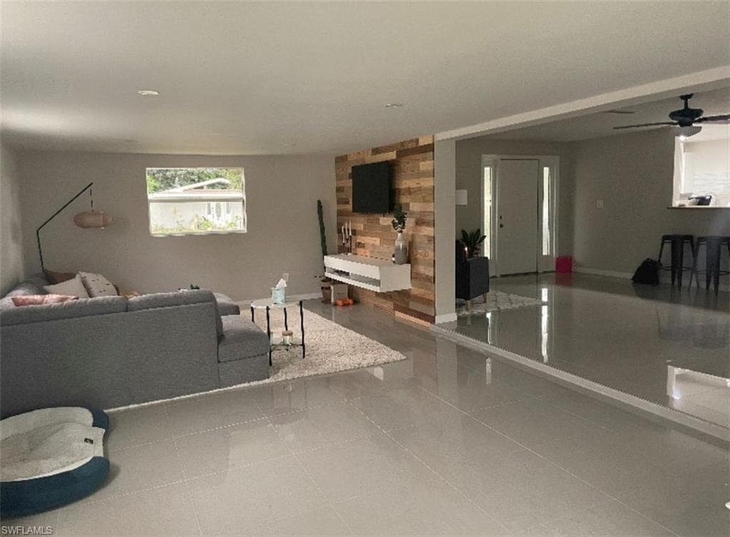 Living room featuring ceiling fan and wood walls