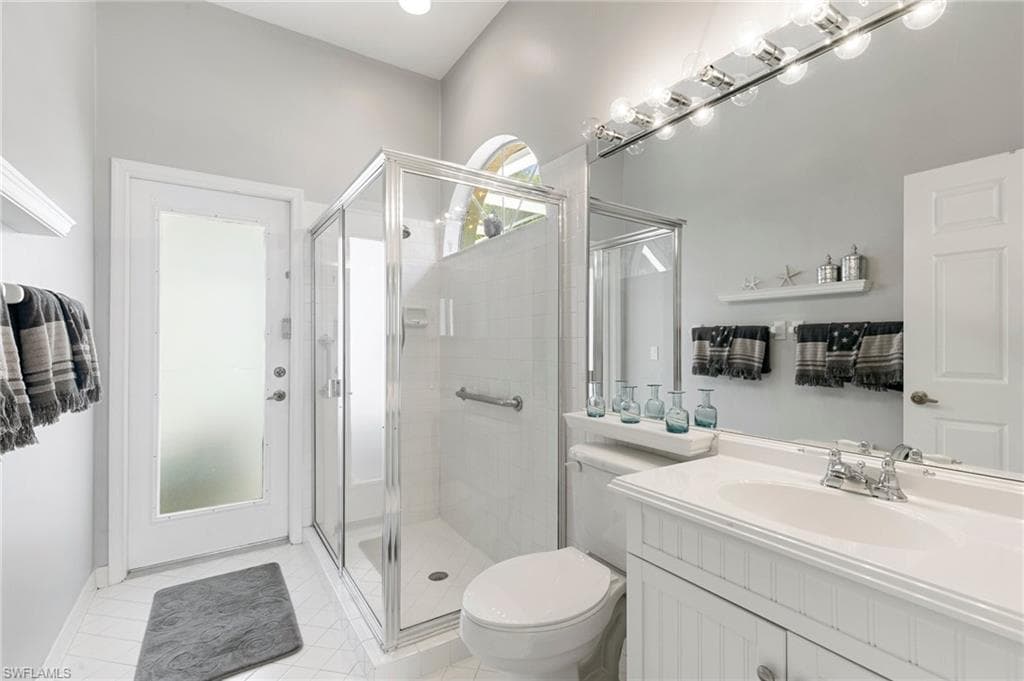 Bathroom with tile patterned floors, vanity, toilet, and an enclosed shower