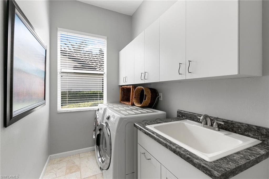 Laundry room featuring washer and clothes dryer, plenty of natural light, cabinets, and sink