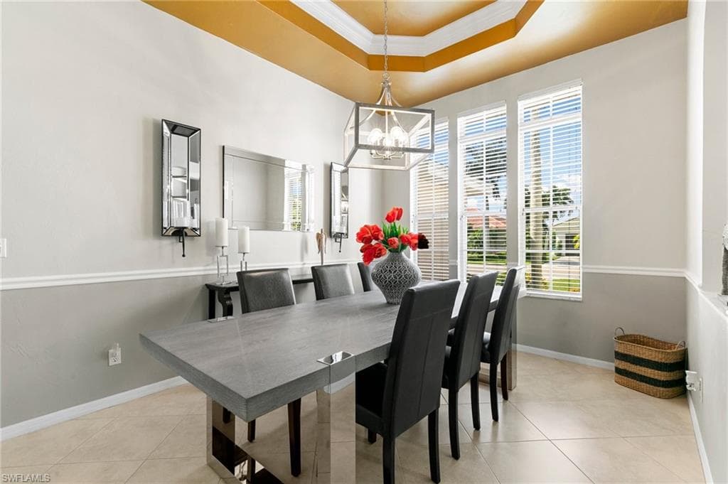 Dining area with a chandelier, light tile patterned floors, and a healthy amount of sunlight