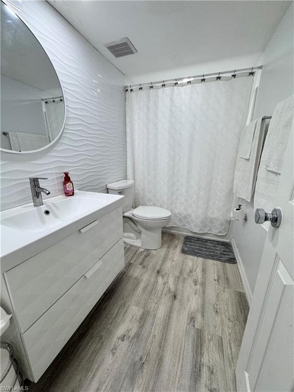 Full bathroom with vanity, light wood-type flooring, tile walls, and shower / bath combo