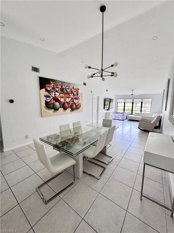 Dining area featuring vaulted ceiling, light tile patterned flooring, and hanging lights