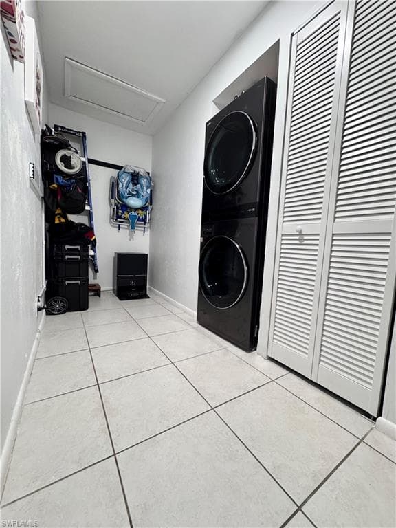 Laundry area with stacked washer / drying machine and light tile patterned flooring