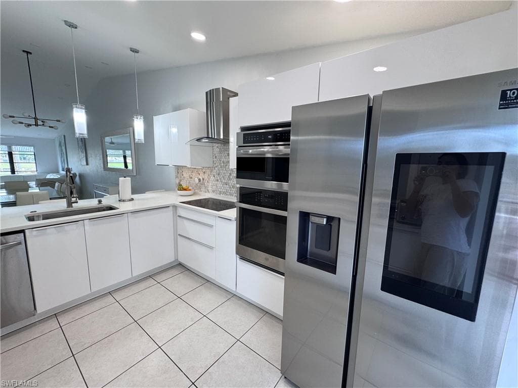 Kitchen featuring stainless steel appliances, white cabinets, open floor plan, tasteful backsplash, and modern cabinets
