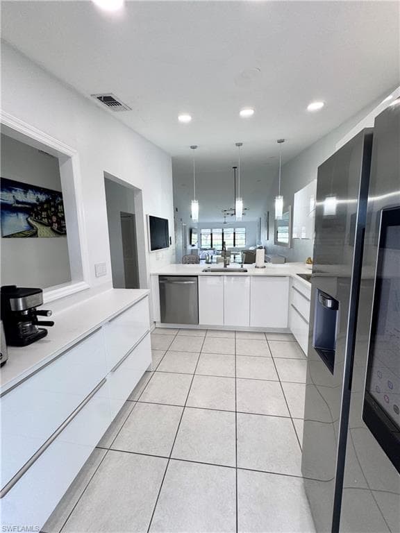 Kitchen featuring white cabinetry, modern cabinets, stainless steel appliances, pendant lighting, and light tile patterned floors