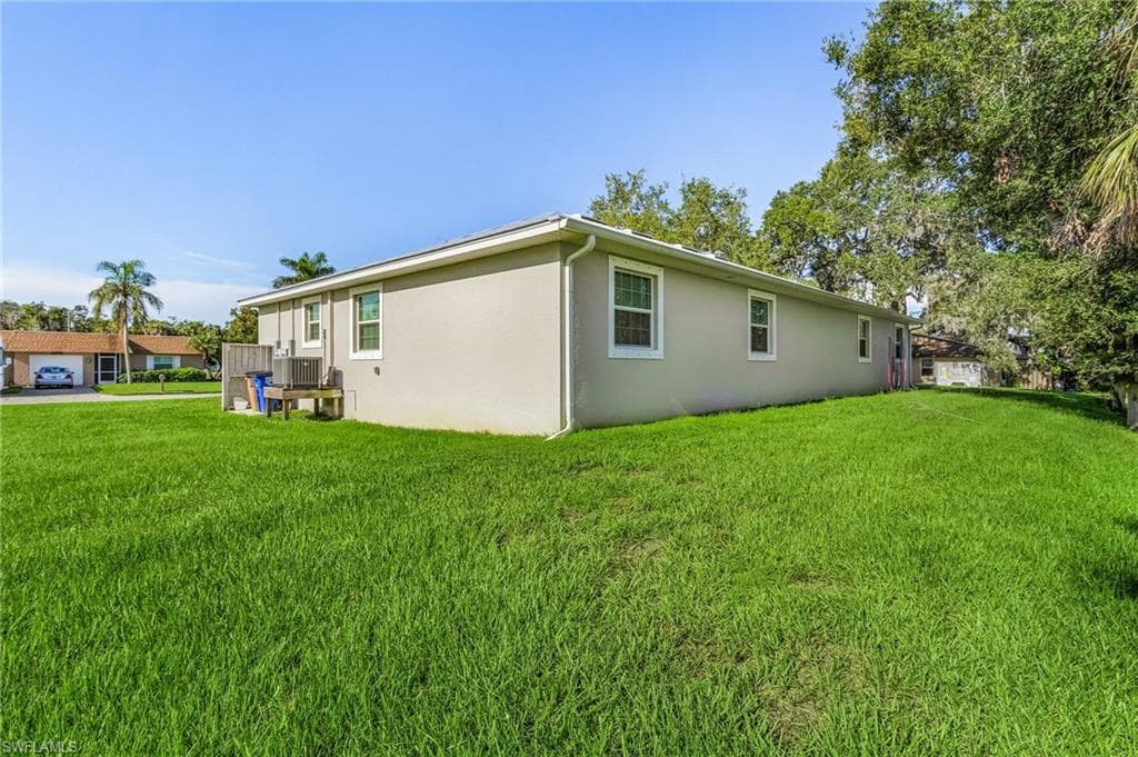 View of side of property featuring a lawn and stucco siding