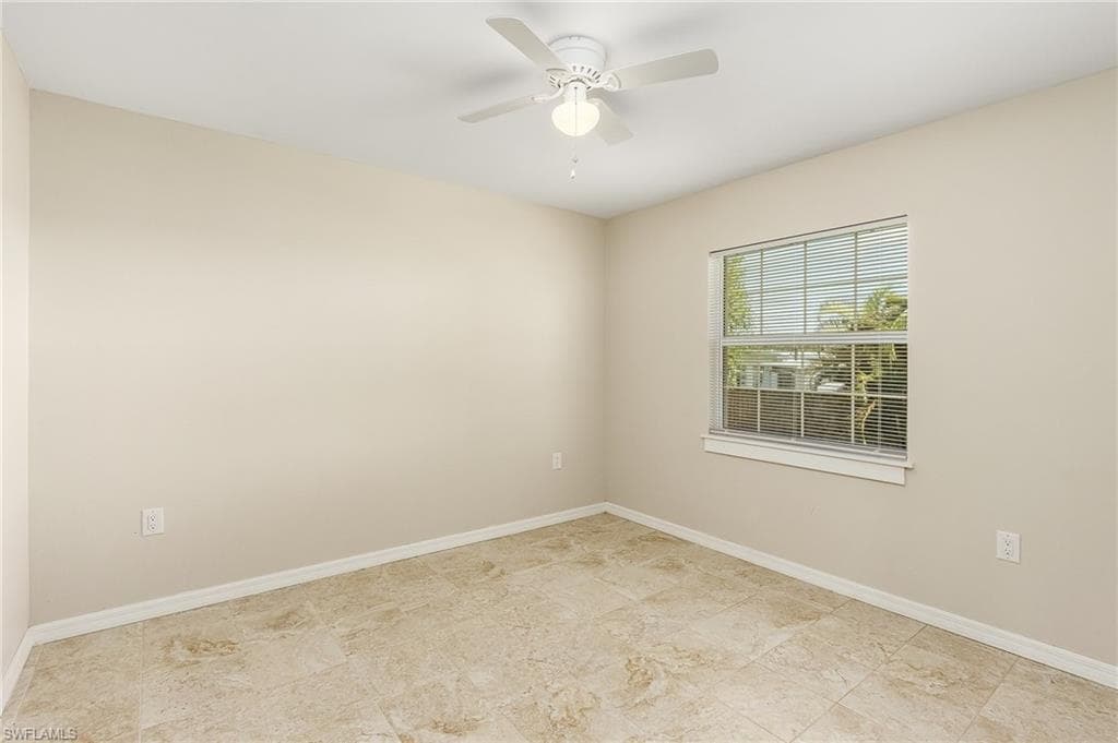 Empty room featuring baseboards and a ceiling fan