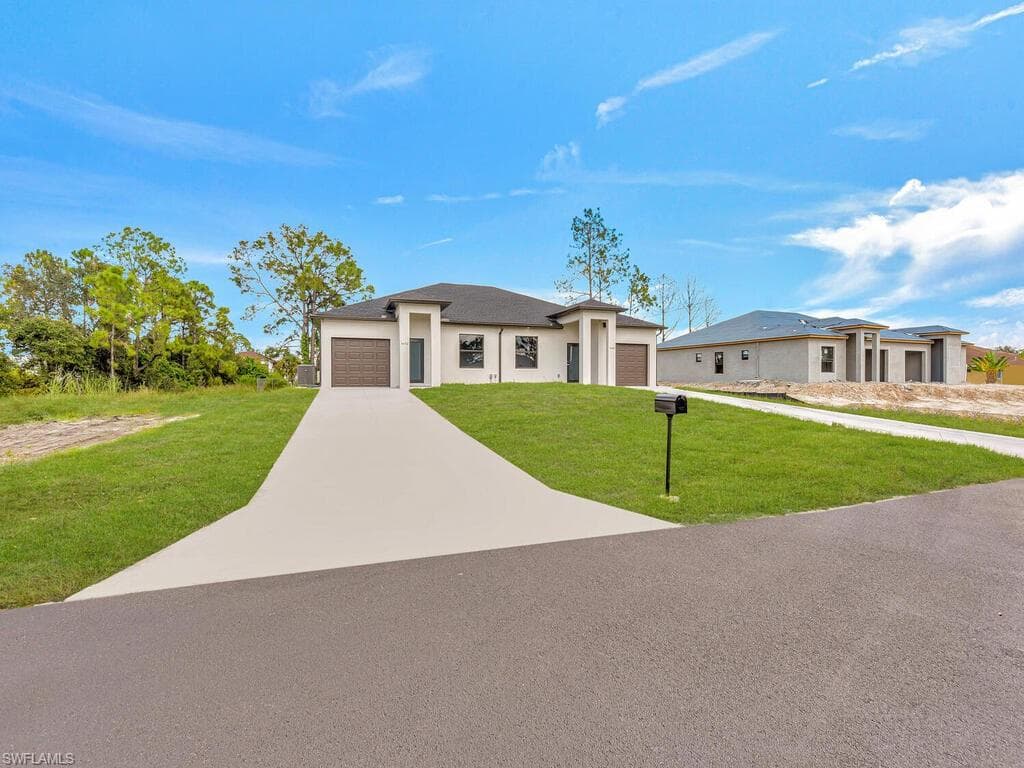 Prairie-style house with an attached garage, driveway, stucco siding, and a front lawn