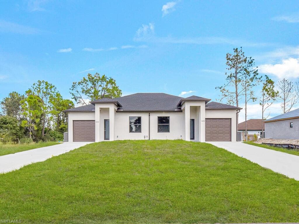 Prairie-style home featuring a front lawn, stucco siding, and a garage
