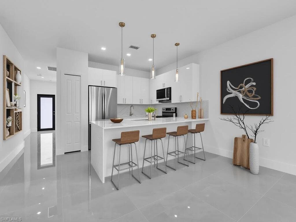Kitchen featuring a breakfast bar area, white cabinets, a peninsula, modern cabinets, and hanging light fixtures