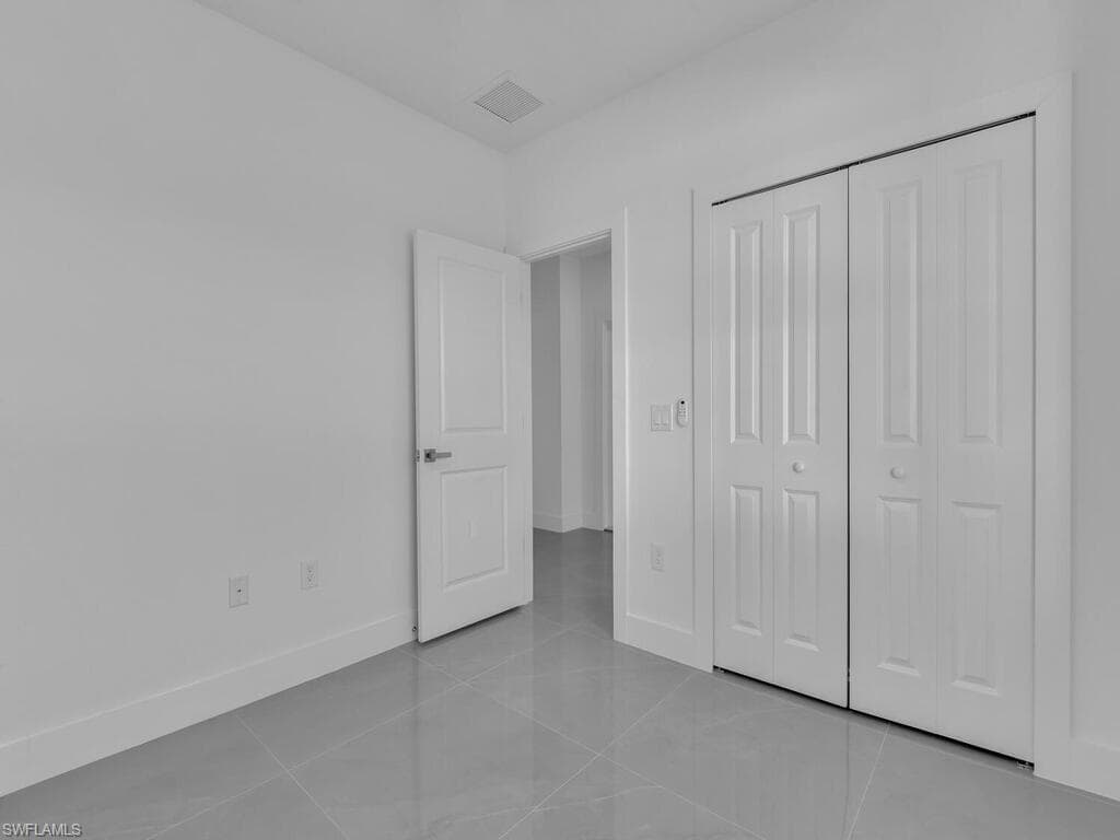Unfurnished bedroom with light tile patterned flooring and a closet