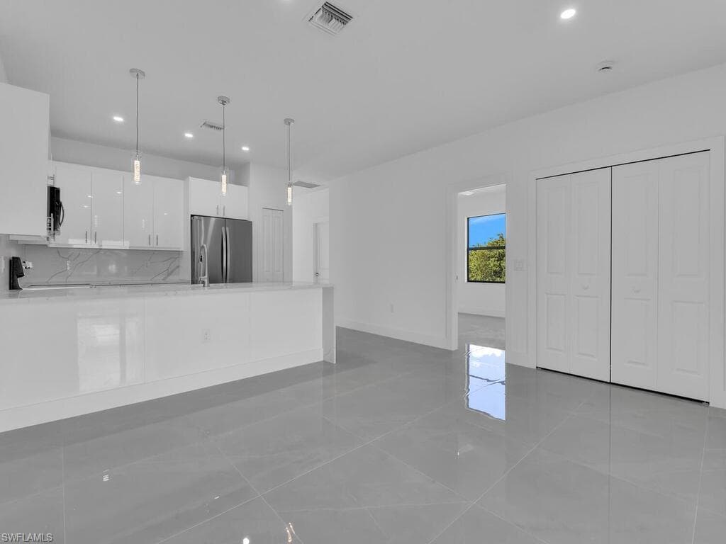 Kitchen with white cabinets, light stone countertops, a peninsula, pendant lighting, and recessed lighting