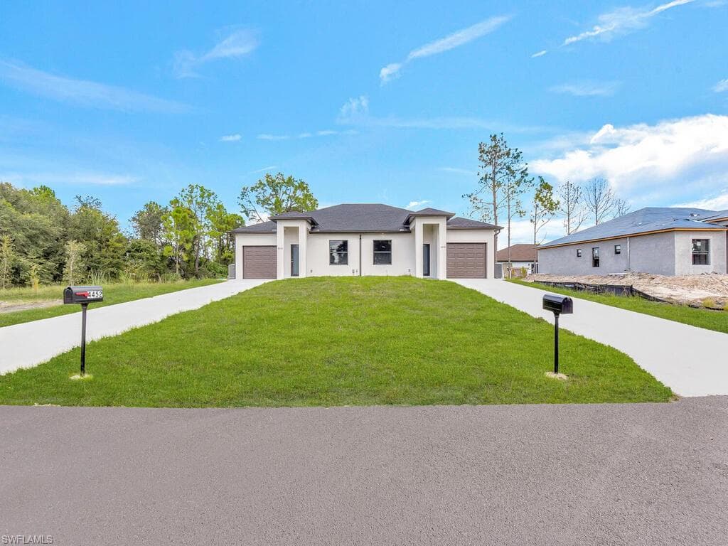 Prairie-style home with driveway, a front lawn, and stucco siding