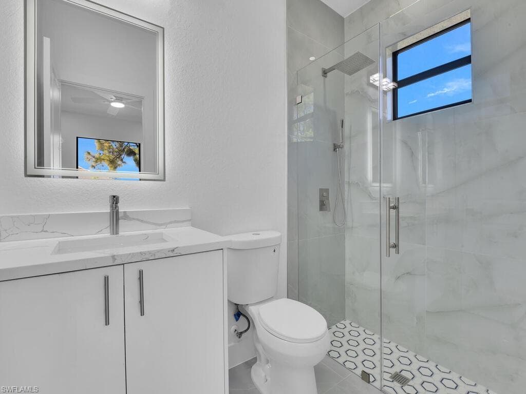 Bathroom featuring vanity, a marble finish shower, a textured wall, and tile patterned flooring