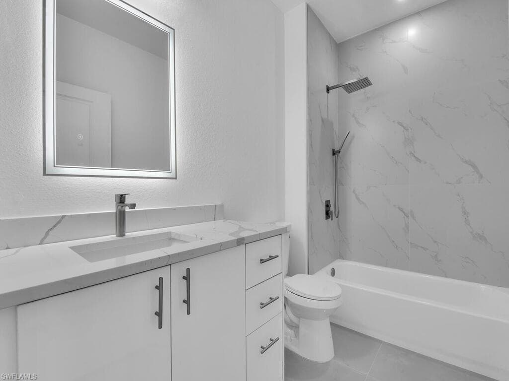 Bathroom with vanity, tile patterned flooring, a combined bath / shower with marble appearance, and a textured wall
