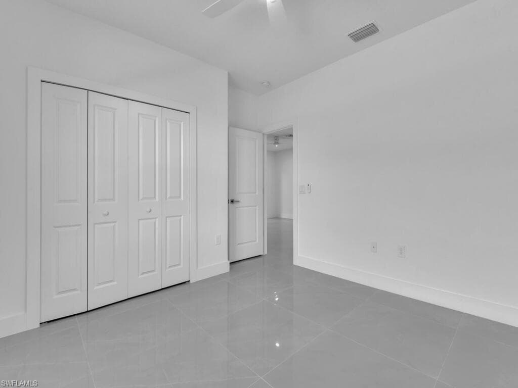 Unfurnished bedroom with light tile patterned floors, a ceiling fan, and a closet