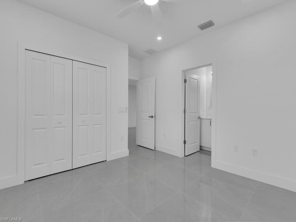 Unfurnished bedroom featuring light tile patterned flooring, ensuite bath, ceiling fan, a closet, and recessed lighting
