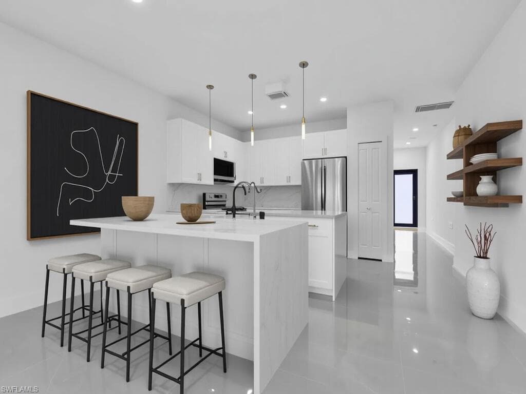 Kitchen featuring white cabinetry, a breakfast bar area, light stone counters, hanging light fixtures, and recessed lighting