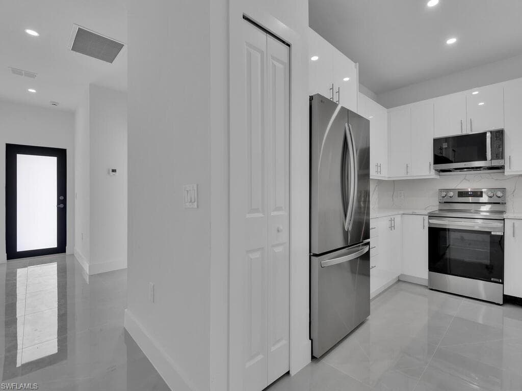 Kitchen with recessed lighting, stainless steel appliances, white cabinets, modern cabinets, and light stone countertops