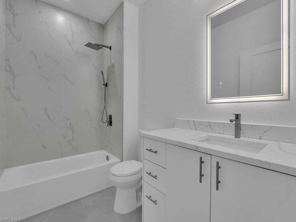 Bathroom featuring vanity, a combined bath / shower with marble appearance, and light tile patterned floors