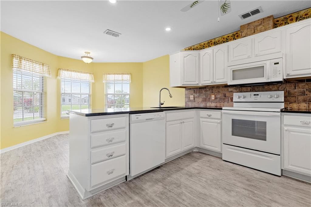 Overlooking back windows and dining area. Granite countertops and white wood cabinates.