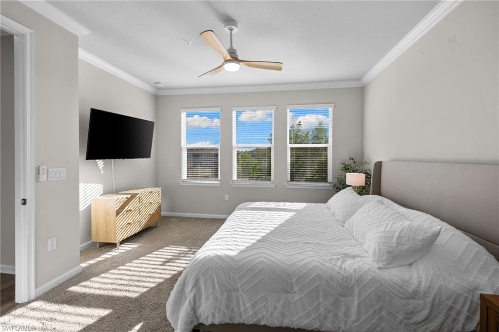 Carpeted bedroom featuring crown molding and a ceiling fan