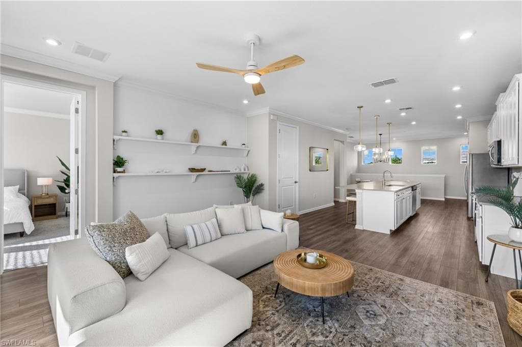 Living area featuring dark wood-style flooring, ceiling fan, crown molding, and recessed lighting