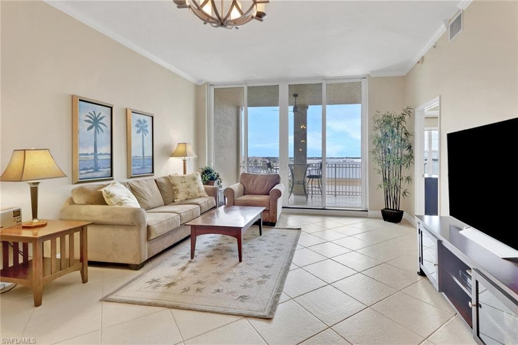 Living area featuring a wall of windows, crown molding, light tile patterned floors, and a chandelier