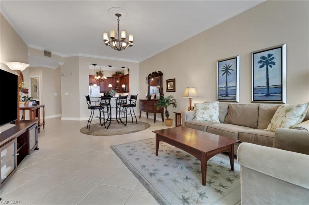 Living area with crown molding, a chandelier, and light tile patterned flooring