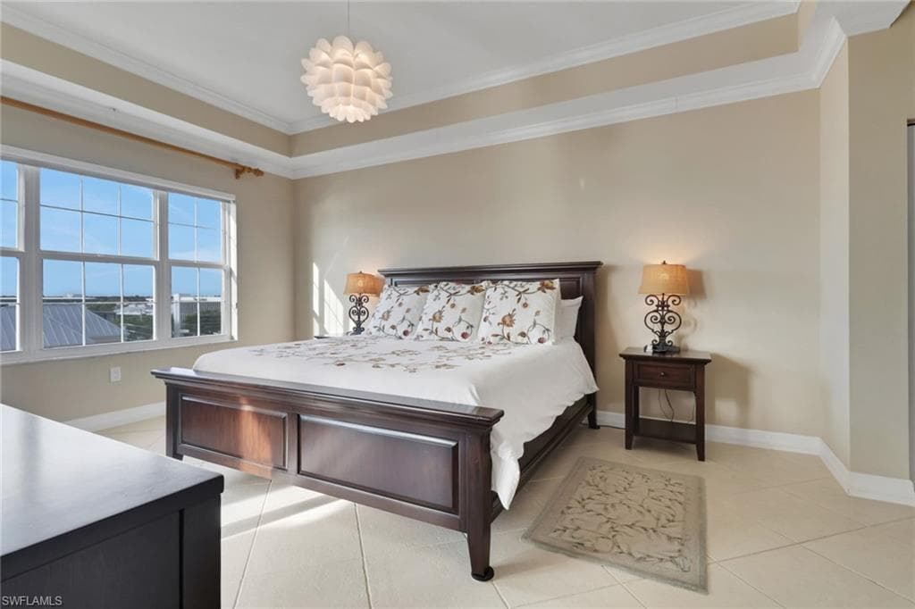 Bedroom featuring crown molding, light tile patterned floors, and a raised ceiling