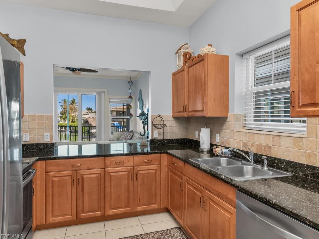 Kitchen with stainless steel appliances, brown cabinets, light tile patterned flooring, and tasteful backsplash