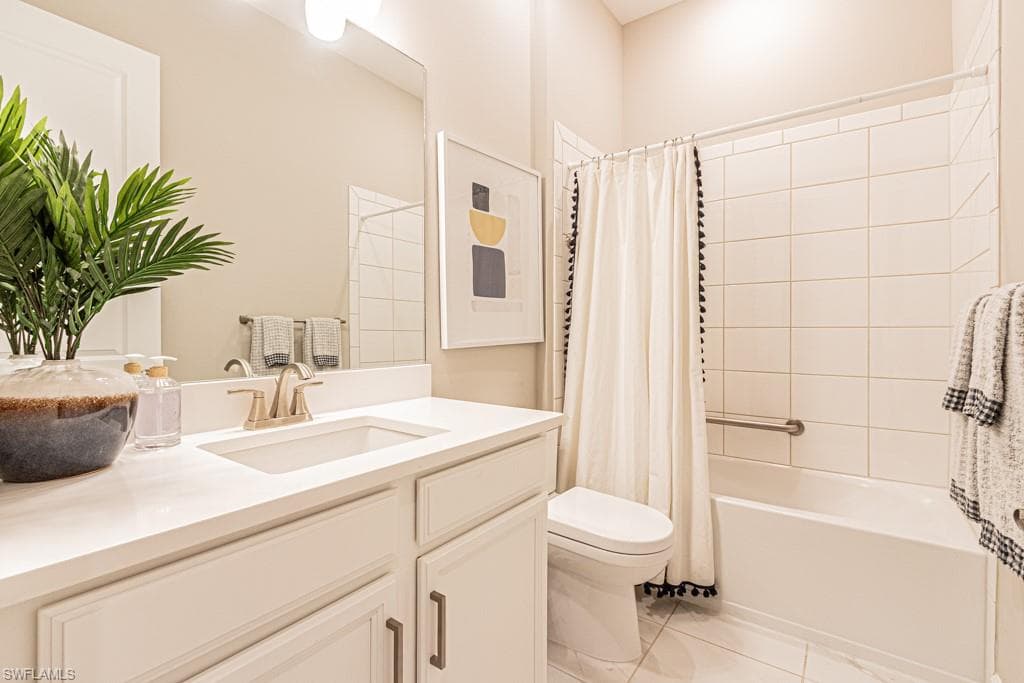 Bathroom featuring shower / tub combo, vanity, and light tile patterned flooring
