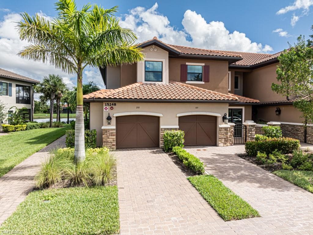 Mediterranean / spanish-style home featuring stone siding, decorative driveway, a tiled roof, and stucco siding