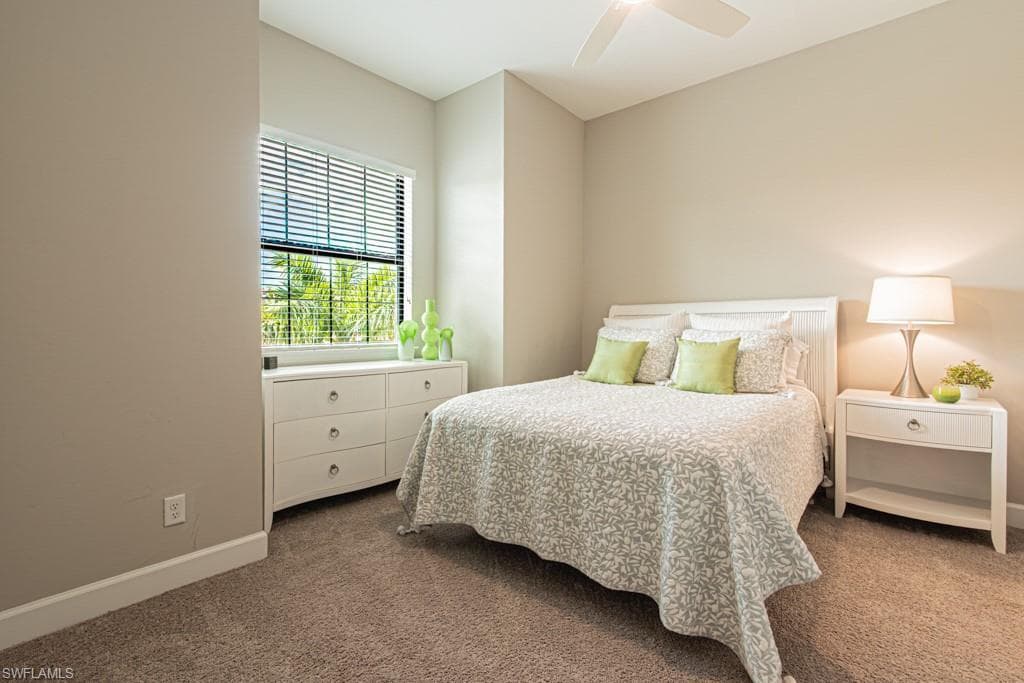Carpeted bedroom with a ceiling fan and baseboards
