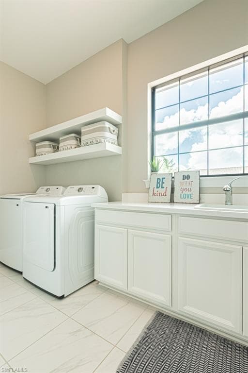 Laundry room featuring washer and dryer, cabinet space, and light tile patterned floors