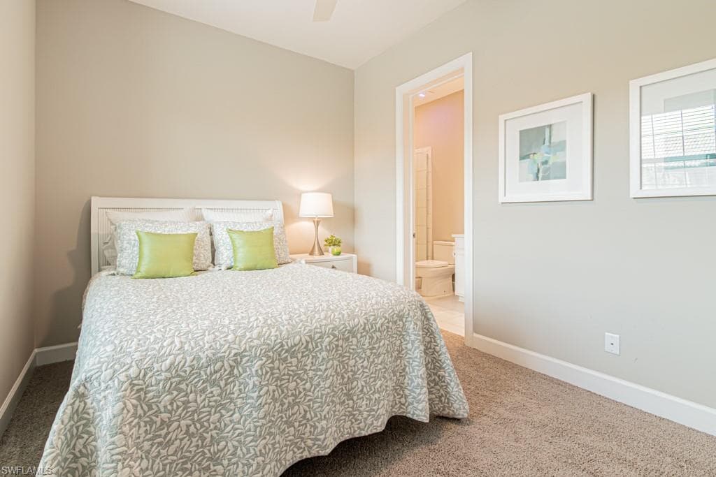 Bedroom with light carpet, ceiling fan, and ensuite bathroom