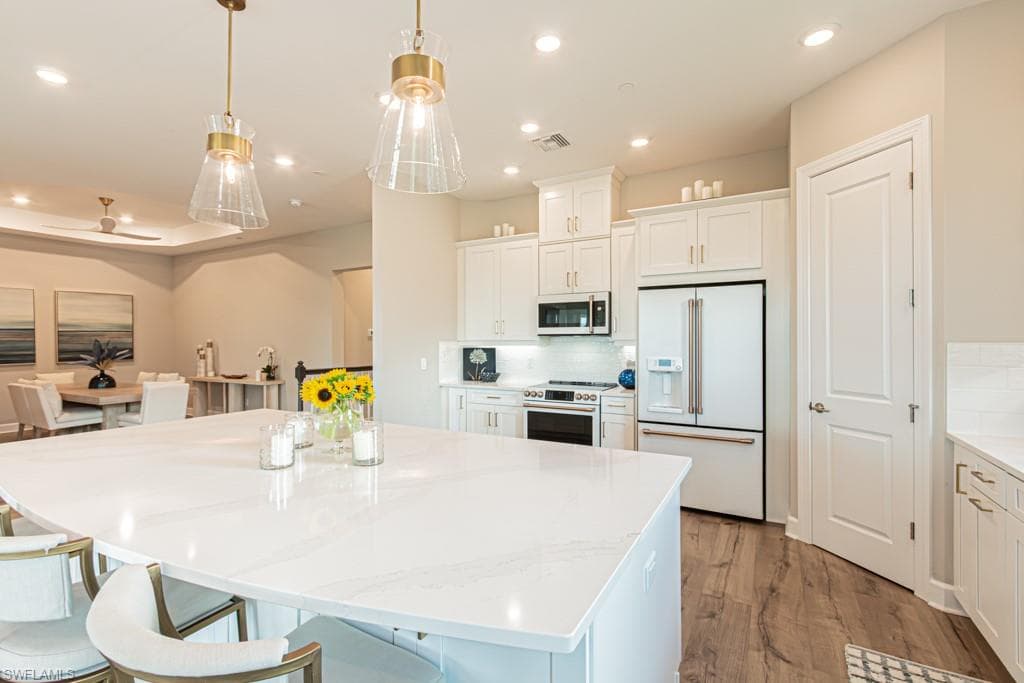 Kitchen with white cabinets, white appliances, a center island, backsplash, and recessed lighting