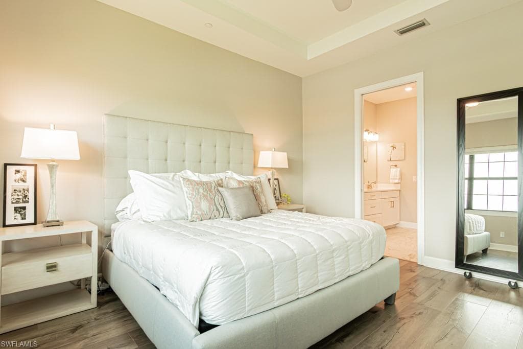 Bedroom with wood finished floors and connected bathroom