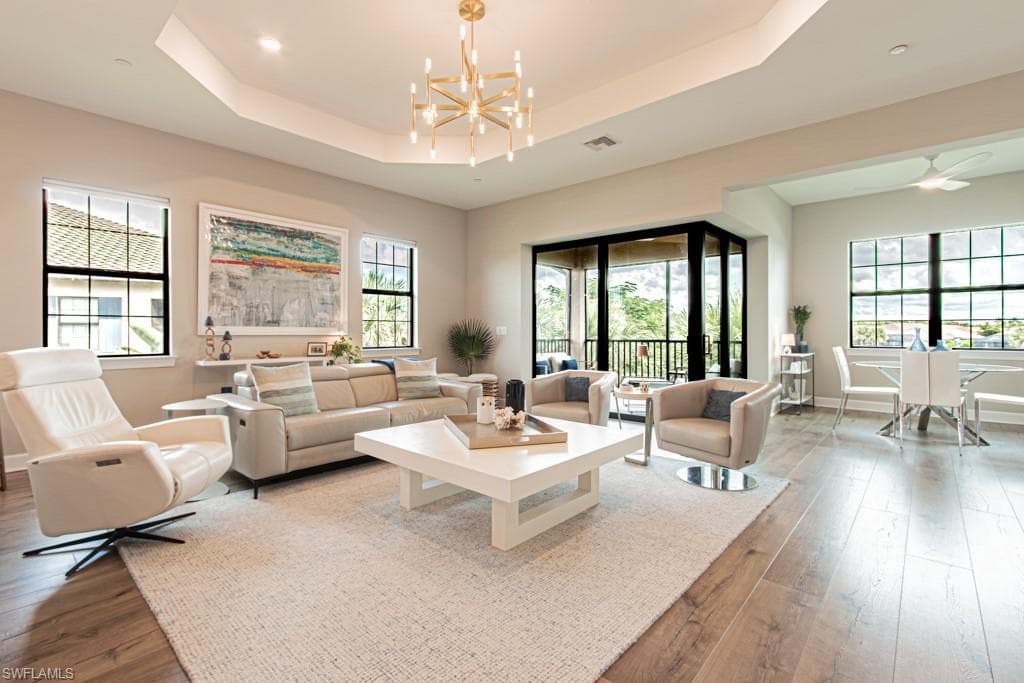 Living area featuring a tray ceiling, a chandelier, and hardwood / wood-style flooring