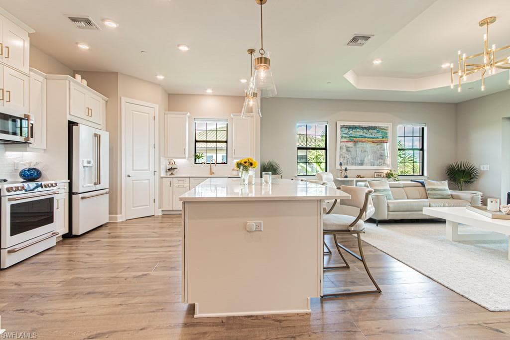 Kitchen featuring white appliances, open floor plan, light wood finished floors, plenty of natural light, and recessed lighting