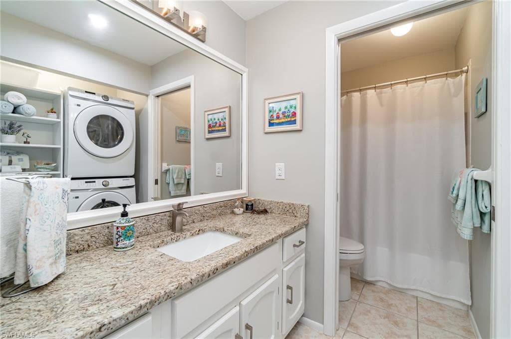 Guest bathroom featuring granite counter, light tile floors, and slider door to toilet and shower/tub combo