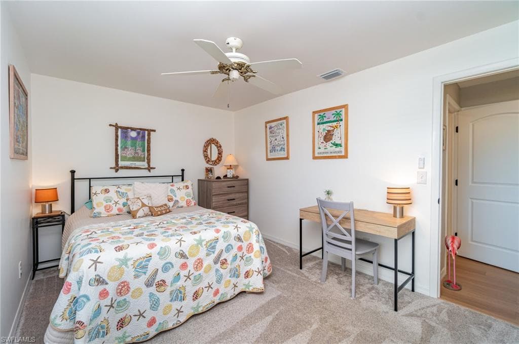Guest bedroom with queen bed, light colored carpet, and ceiling fan