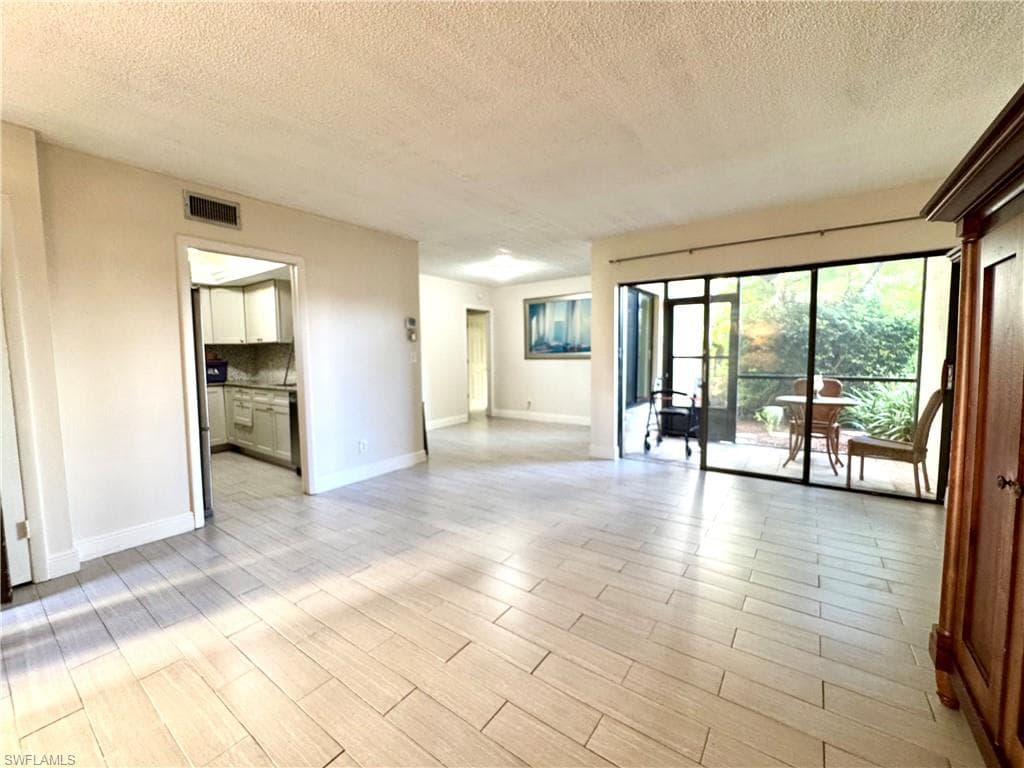 Empty room with a textured ceiling and light wood-style flooring