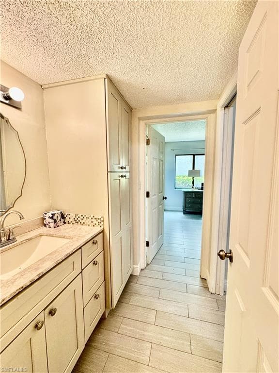 Bathroom with vanity, a textured ceiling, and wood tiled floors