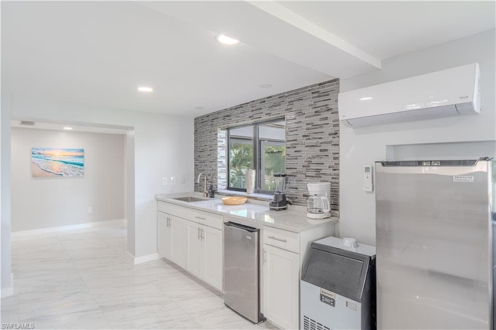Kitchen with white cabinetry, backsplash, a wall unit AC, light stone counters, and recessed lighting - Virtually Edited Image